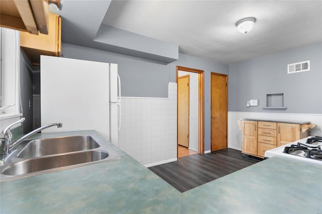 kitchen with visible vents, dark wood-style floors, freestanding refrigerator, gas range oven, and a sink