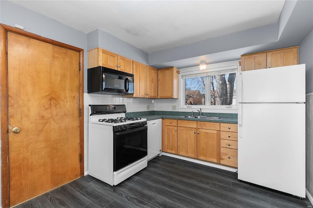 kitchen with white appliances, a sink, tasteful backsplash, dark countertops, and dark wood finished floors