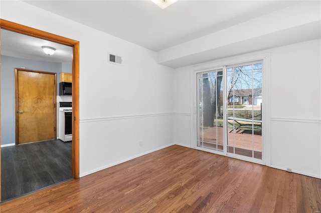 spare room featuring visible vents, baseboards, and wood finished floors