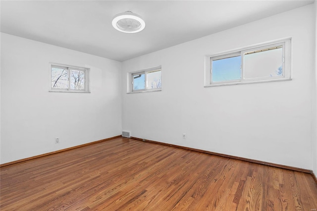 spare room featuring baseboards, visible vents, and light wood finished floors