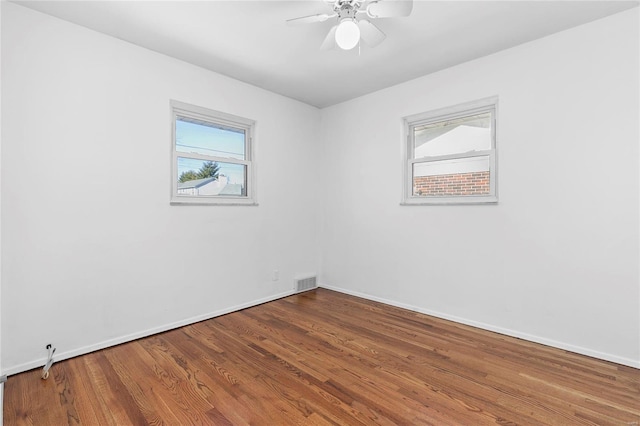 spare room with a ceiling fan, baseboards, visible vents, and wood finished floors