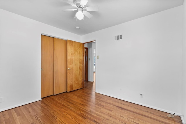 unfurnished bedroom with baseboards, visible vents, a ceiling fan, wood finished floors, and a closet