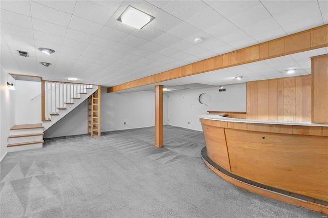 bar featuring wooden walls, carpet flooring, visible vents, stairs, and a bar