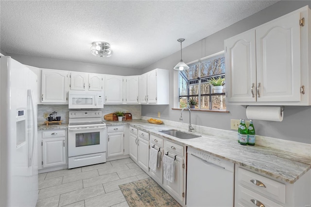 kitchen with white appliances, white cabinets, light stone countertops, and a sink