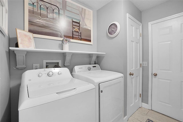 clothes washing area with separate washer and dryer, laundry area, and a textured ceiling