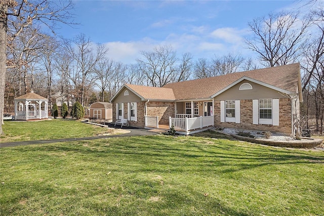 view of front of home with a gazebo, an outbuilding, brick siding, and a front yard