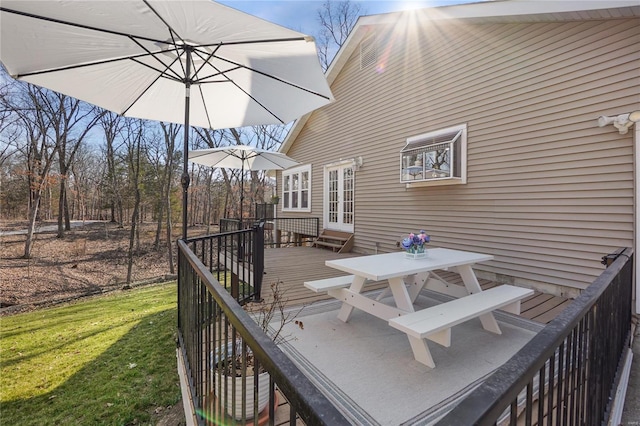 wooden deck featuring outdoor dining space, a yard, and french doors