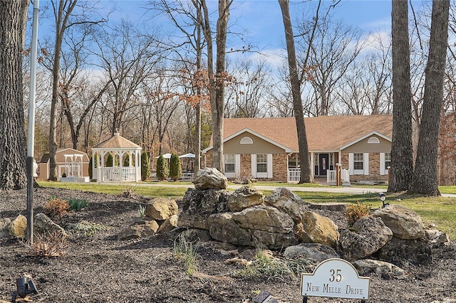 view of front of property featuring a gazebo and brick siding