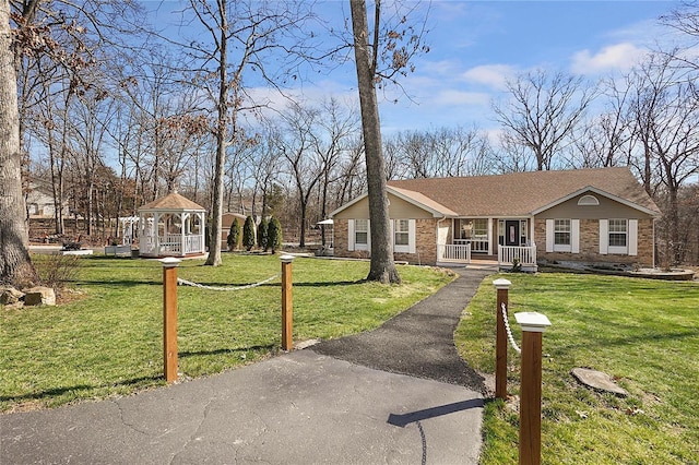 view of front facade with a gazebo, driveway, brick siding, and a front lawn