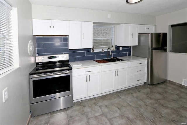 kitchen with stainless steel appliances, white cabinets, a sink, and decorative backsplash