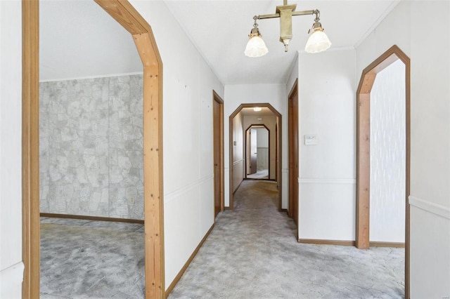 hall with arched walkways, baseboards, and carpet floors