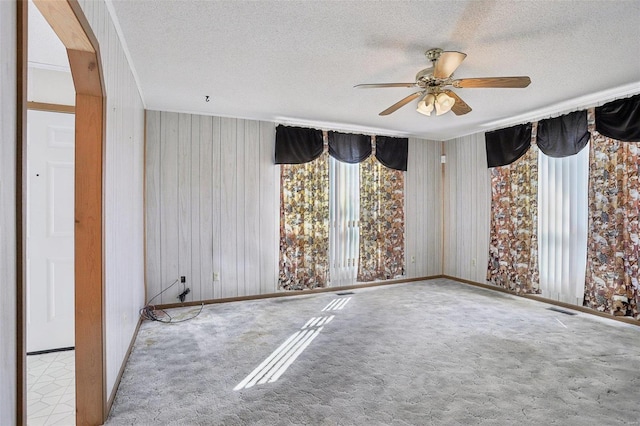 empty room with carpet flooring, a textured ceiling, visible vents, and a ceiling fan