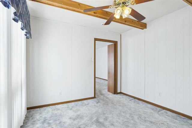 carpeted empty room featuring beamed ceiling, baseboards, and ceiling fan