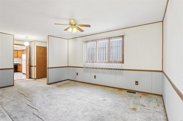 carpeted spare room with visible vents and ceiling fan