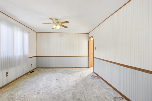 carpeted spare room featuring crown molding and ceiling fan