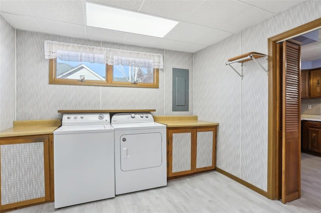 laundry room with washer and clothes dryer, electric panel, cabinet space, light wood-style floors, and wallpapered walls