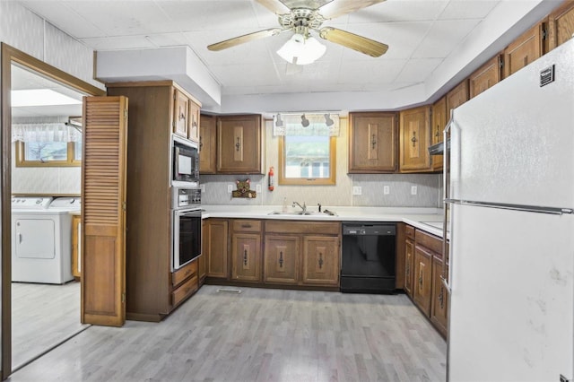 kitchen with black appliances, light countertops, light wood-style floors, and separate washer and dryer