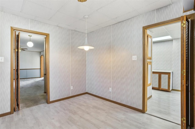 unfurnished room with wallpapered walls, wood finished floors, and baseboards