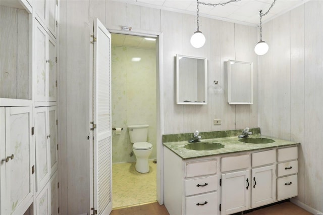 full bathroom with double vanity, ornamental molding, toilet, and a sink