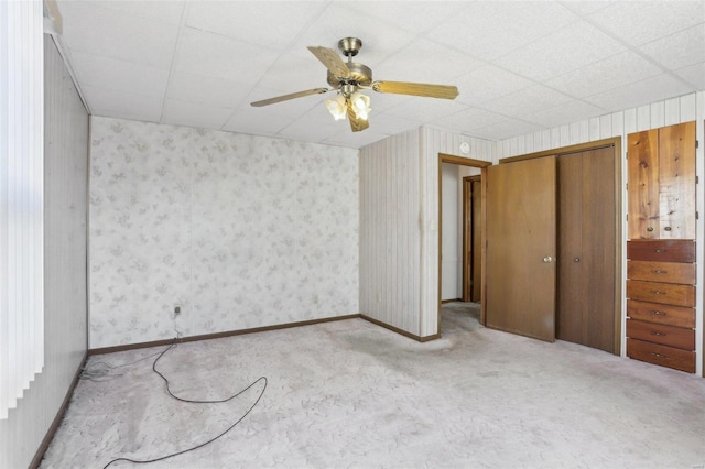 unfurnished bedroom featuring a ceiling fan, a closet, carpet floors, wallpapered walls, and baseboards