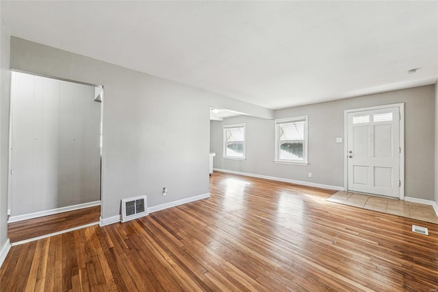 unfurnished living room with visible vents, baseboards, and hardwood / wood-style floors