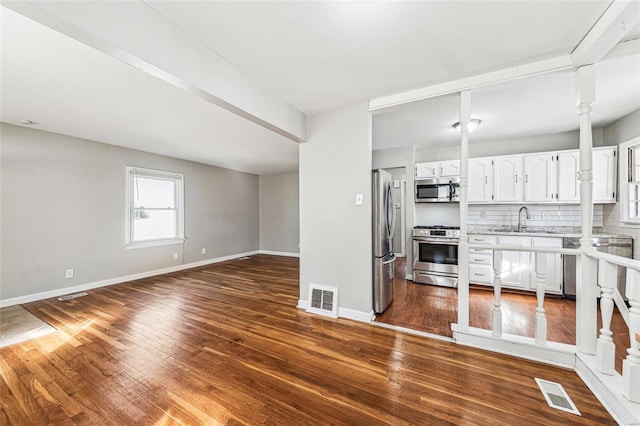 kitchen with a sink, stainless steel appliances, tasteful backsplash, and visible vents