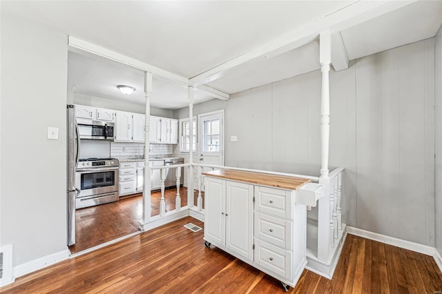 kitchen with tasteful backsplash, dark wood finished floors, stainless steel appliances, white cabinets, and baseboards