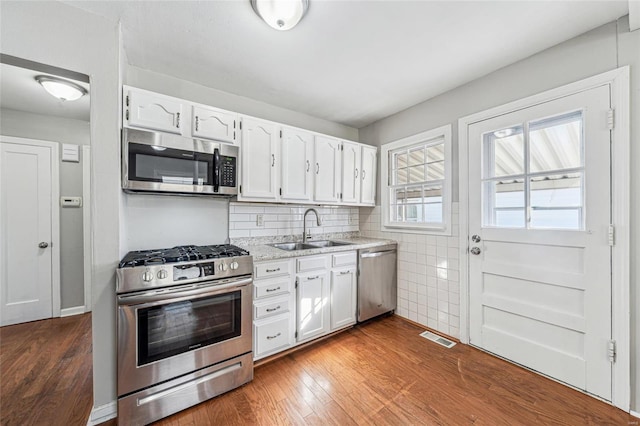 kitchen featuring visible vents, hardwood / wood-style floors, appliances with stainless steel finishes, white cabinets, and a sink