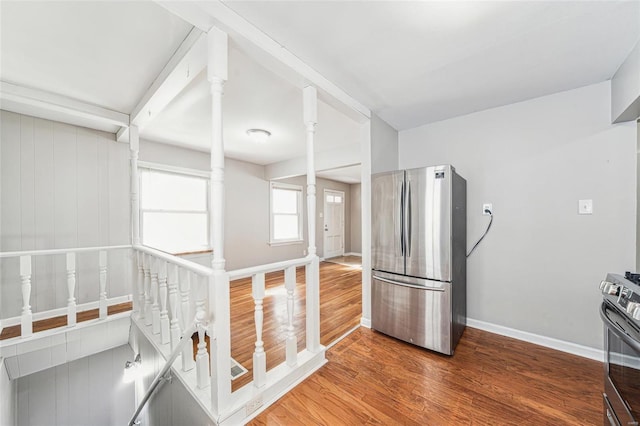 kitchen with decorative columns, baseboards, appliances with stainless steel finishes, and wood finished floors