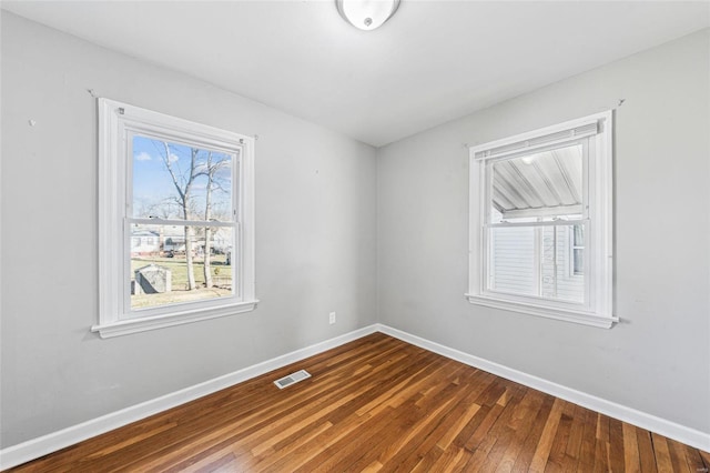 empty room with visible vents, baseboards, and dark wood-style floors