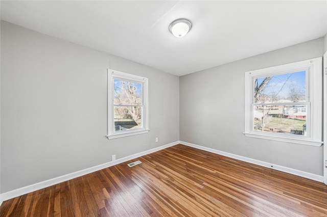 empty room featuring hardwood / wood-style flooring, baseboards, and visible vents