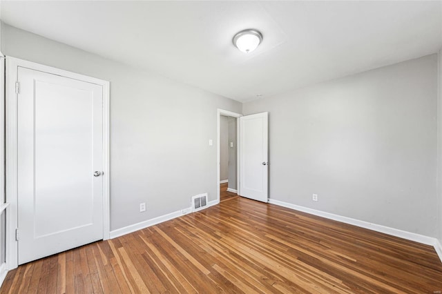 unfurnished bedroom featuring visible vents, baseboards, and hardwood / wood-style floors