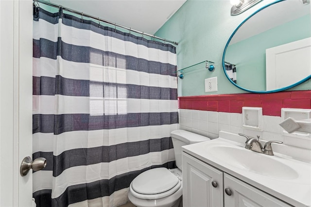 bathroom featuring curtained shower, tile walls, toilet, wainscoting, and vanity