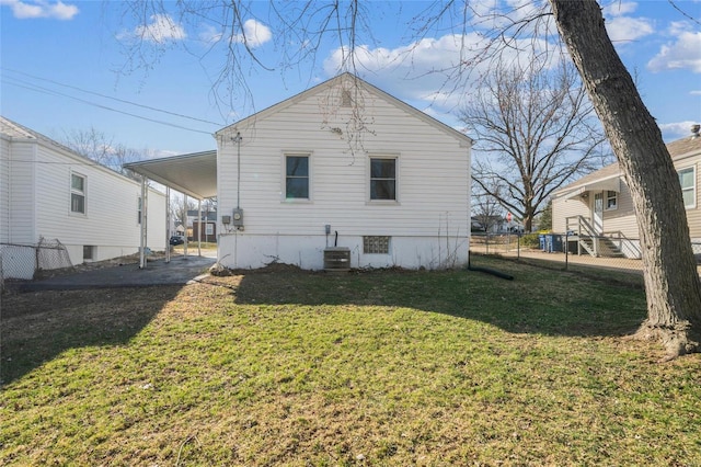 back of property with a yard, an attached carport, central AC unit, and fence