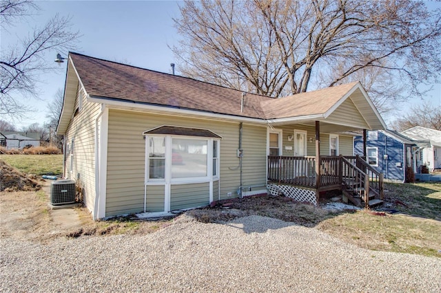 view of front of property featuring cooling unit, covered porch, and a shingled roof