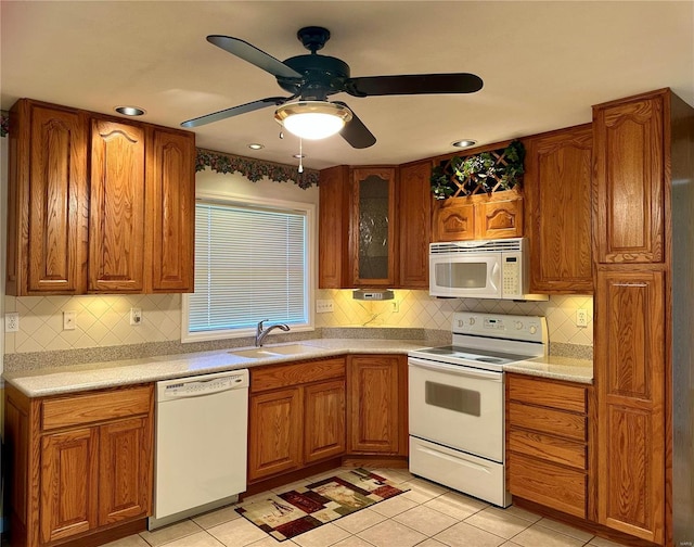 kitchen featuring a sink, glass insert cabinets, white appliances, and brown cabinets