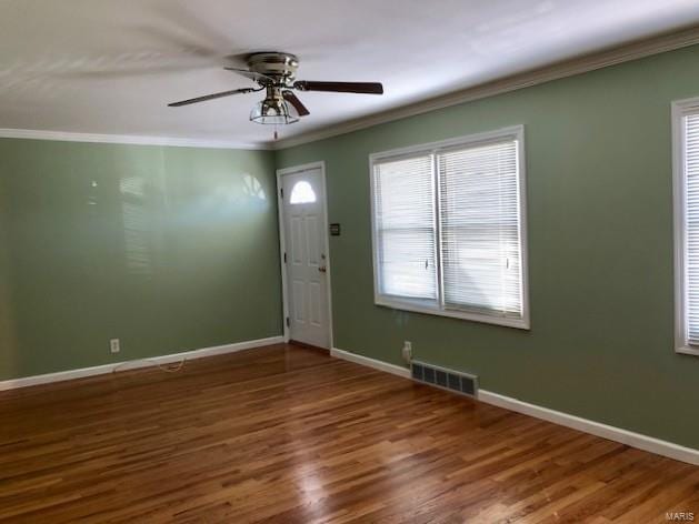 entrance foyer with wood finished floors, visible vents, baseboards, and ornamental molding