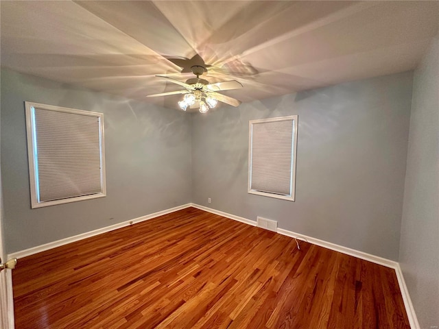 unfurnished room featuring visible vents, a ceiling fan, baseboards, and wood finished floors