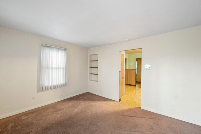 carpeted spare room with built in features and baseboards