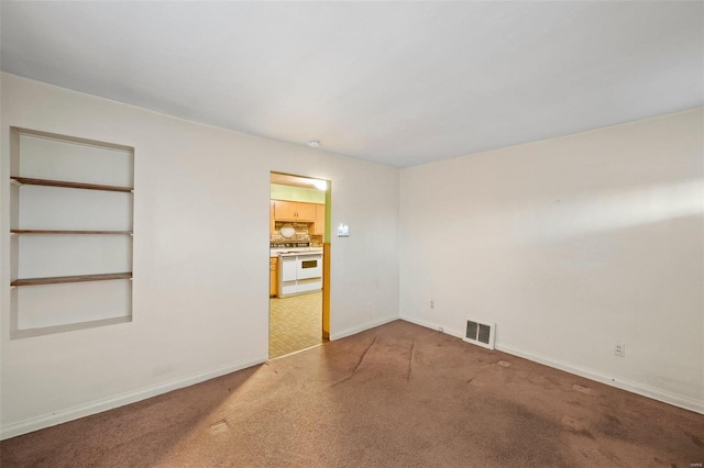 unfurnished room featuring baseboards, visible vents, and light carpet