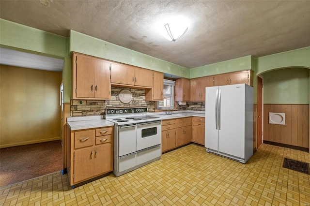 kitchen with white appliances, light countertops, arched walkways, and a sink