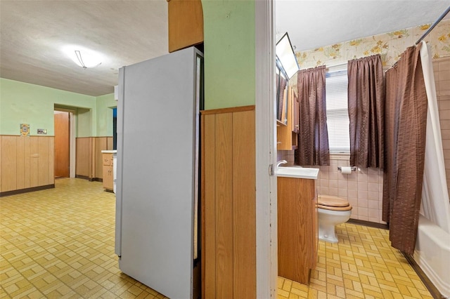 full bathroom with a sink, toilet, a wainscoted wall, and a textured ceiling