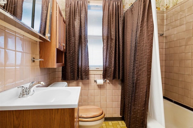 bathroom with toilet, tile walls, vanity, and shower / bathtub combination with curtain