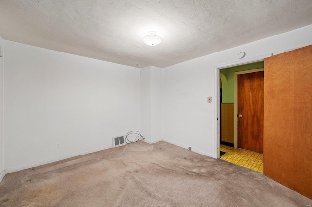 unfurnished room with carpet flooring, visible vents, and a textured ceiling