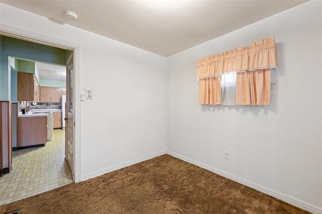 spare room featuring light colored carpet and baseboards