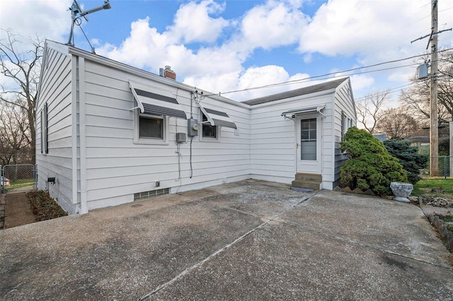 rear view of house featuring entry steps, a chimney, and a patio area