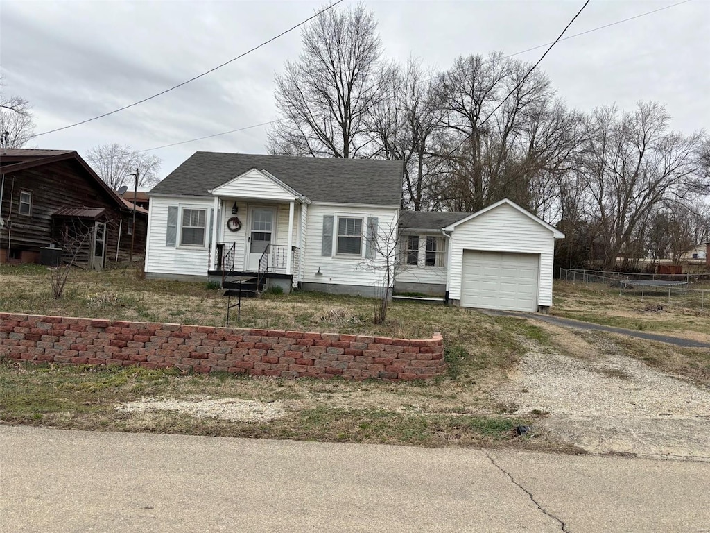 view of front of home with driveway, a shingled roof, a garage, and fence