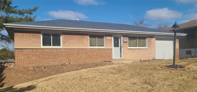 back of property featuring a shingled roof, brick siding, a yard, and an attached garage