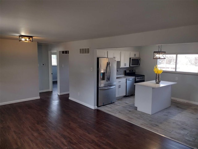 kitchen with visible vents, wood finished floors, stainless steel appliances, light countertops, and white cabinetry