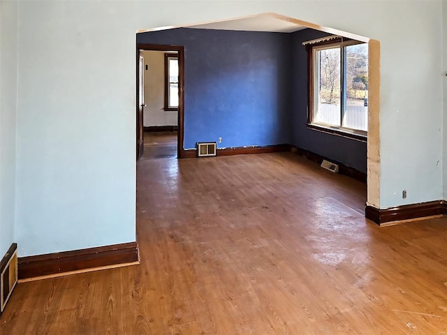 spare room with visible vents, baseboards, and wood finished floors